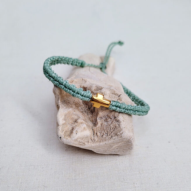 pulsera cruz mint hecha a mano con poliéster encerado y pieza central con baño de oro, cierre ajustable con nudo corredero